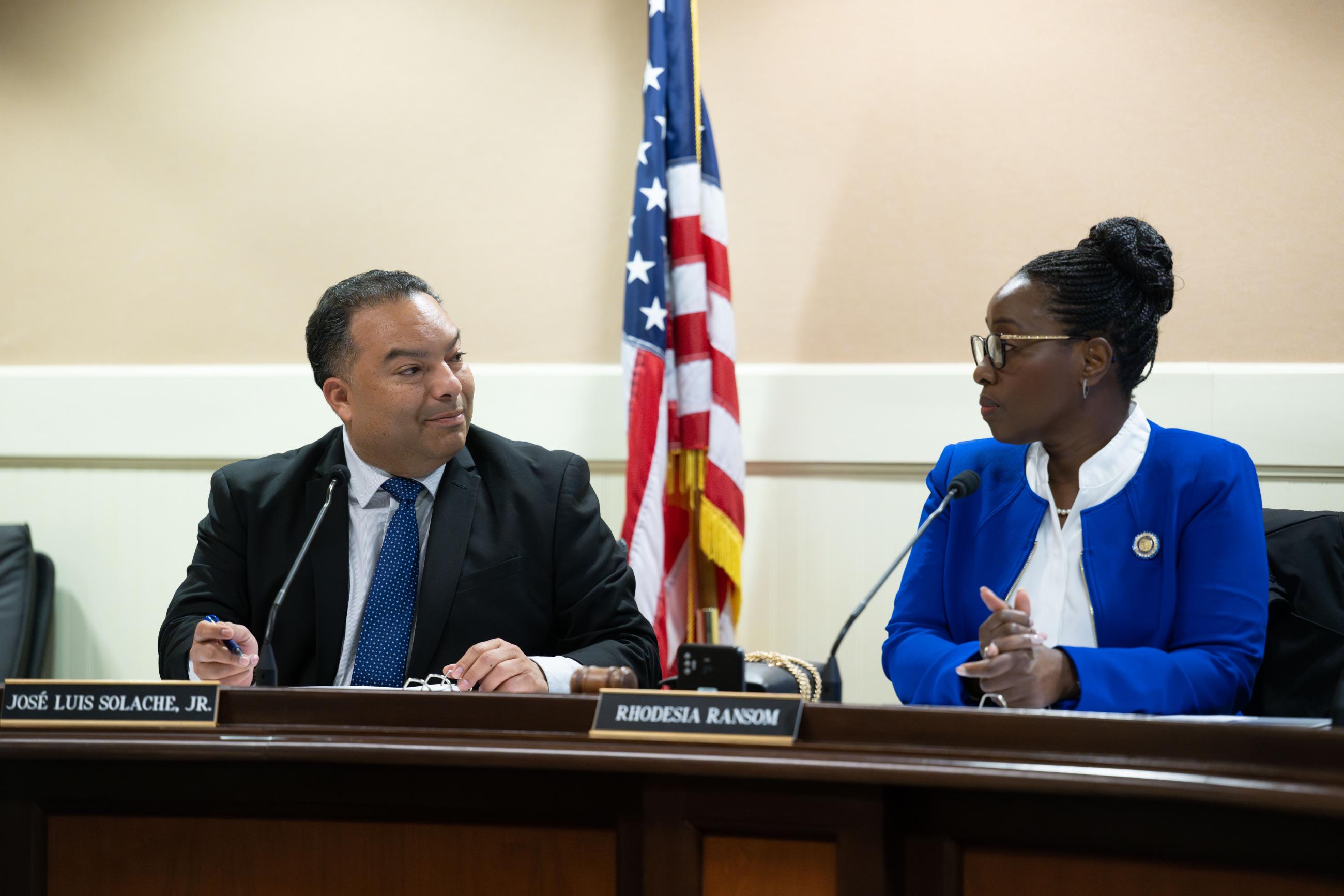 Asm. Solache conversing with Asm. Ransom, both seated at long desk