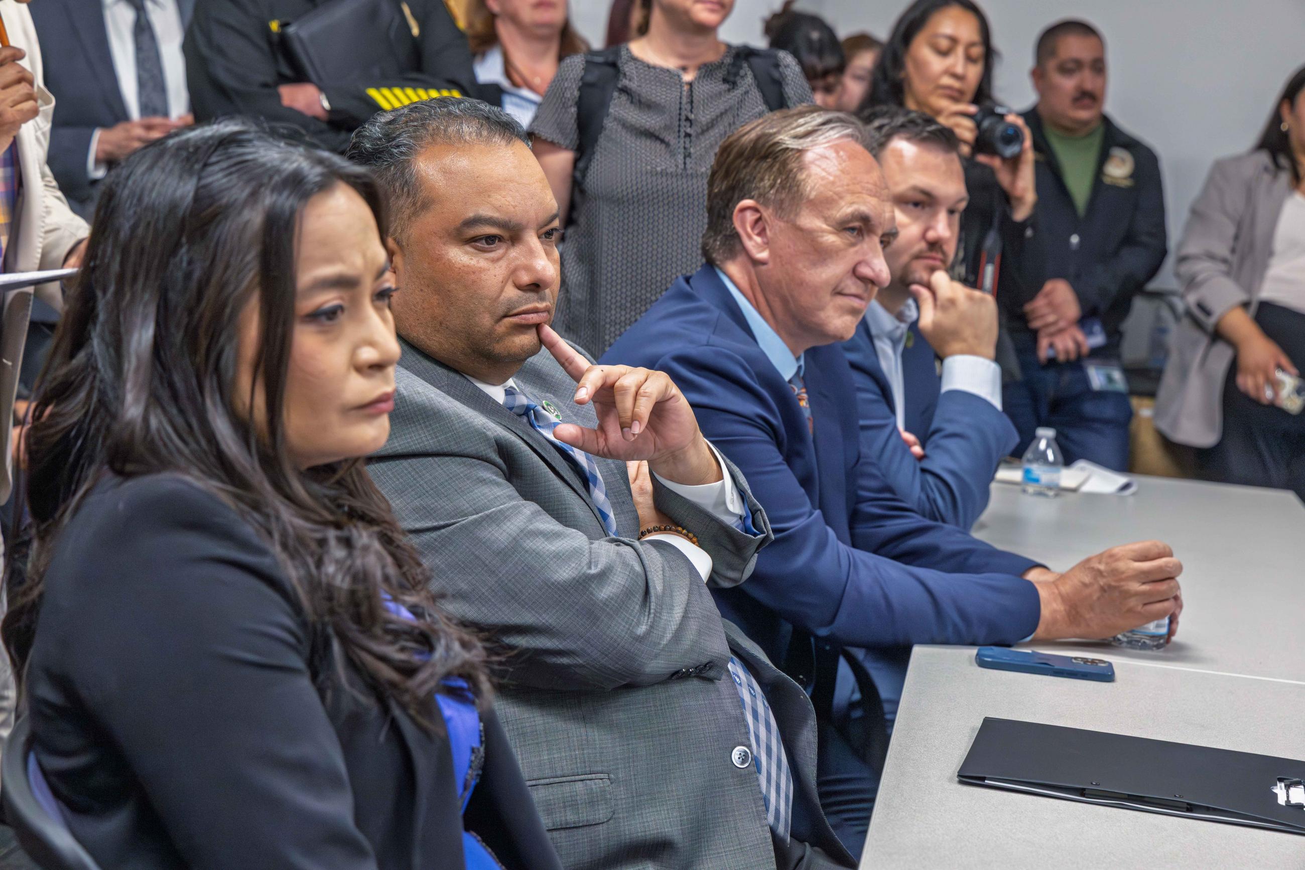 Asm. Solache seated at table with other members, listening on