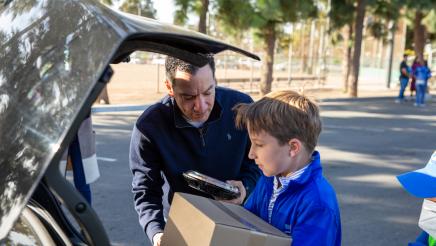 Speaker Rendon assisting young volunteer with box placement in trunk
