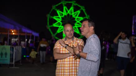 Speaker Emeritus Rendon and attendee conversing, with large green ferris wheel in background
