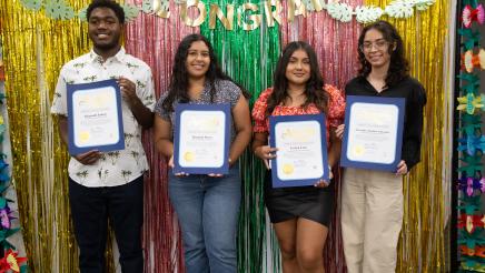 Students holding up certificates in front of festive background