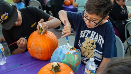 Kids painting pumpkins on table