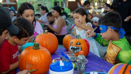 Kids and adults painting pumpkins on table