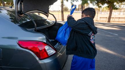 Youth placing food bag into open trunk
