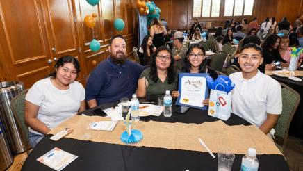 Program participant, with family members, displaying award