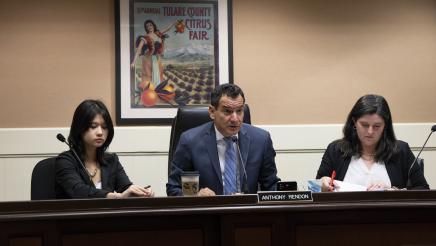 Speaker Emeritus Rendon seated at desk, speaking, with aides seated on either side