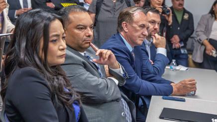 Asm. Solache seated at table with other members, listening on